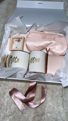 two coffee mugs in a gift box with pink satin ribbon on the floor next to it