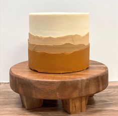 a white and yellow cake sitting on top of a wooden stand next to a wall