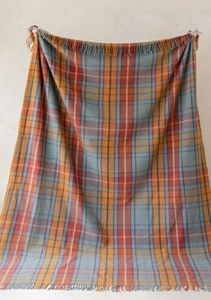 an orange and blue plaid blanket hanging on a wall