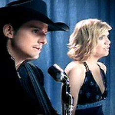 two people standing next to each other with microphones in front of them and one person wearing a cowboy hat