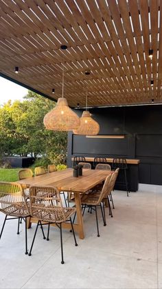 an outdoor dining area with wooden tables and wicker chairs, hanging lights over the table