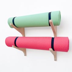 two pink and green yoga mats sitting on top of each other in front of a white wall