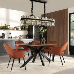 a dining room table with orange chairs and a chandelier hanging from the ceiling