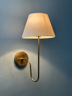 a lamp that is on the wall next to a light fixture with a white shade