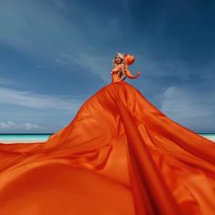 a woman in an orange dress on the beach