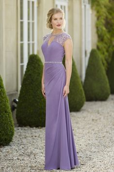 a woman standing in front of a building wearing a purple dress with beading on it