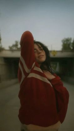 a woman in a red and white sweater is holding her hand up to the side