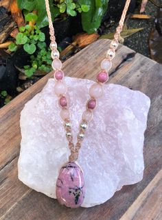 Pink Rhodonite Pendant, threaded on a beaded light brown macrame necklace. Featuring rose quartz, pink Rhodonite and silver brass beads. Adjustable length. Pendant height 2.9cm x 1.7cm width A gorgeous juicy pink colored piece of polished rhodonite. It is lovely on both sides so can be worn either way.  Immerse yourself in the emotional embrace of Rhodonite, a stone revered for its compassion and ability to balance emotions. Each element in this necklace has been carefully curated to not only sh Pink Hand-wrapped Necklace For Jewelry Making, Handmade Spiritual Pink Beaded Necklaces, Handmade Pink Spiritual Beaded Necklace, Hand Wrapped Pink Spiritual Necklaces, Bohemian Rose Quartz Necklace For Healing, Pink Spiritual Hand Wrapped Necklaces, Bohemian Pink Crystal Pendant Necklace, Bohemian Pink Pendant Crystal Necklace, Spiritual Pink Hand Wrapped Necklaces