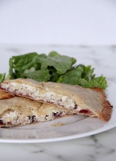 two pastries sitting on top of a white plate next to a green leafy salad