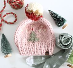 a pink knitted hat sitting on top of a table next to some christmas decorations