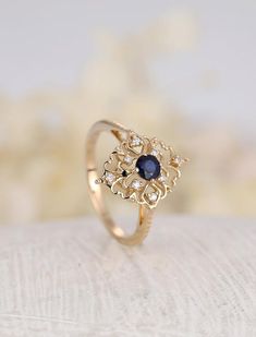 a gold ring with a blue stone in the center on top of a white surface