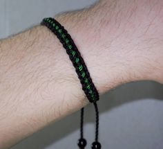 Black braided bracelet with a green line, this bracelet is adjustable to fit wrist sizes from 6 to 9 inches, with an easy to use zip like function to fit your wrist, you'll have it on as soon as you get it. Made from high quality string, it will be sure to last. Each bracelet is carefully handcrafted and give proper time to ensure quality. Fast and Free shipping Handmade Black Nylon Cord Bracelets, Casual Braided Beaded Bracelets As Gift, Casual Braided Beaded Bracelets For Gift, Casual Resizable Wristband As Gift, Adjustable Casual Bracelet With Nylon Cord, Casual Green Friendship Bracelets With Adjustable Cord, Casual Green Friendship Bracelet With Adjustable Cord, Casual Braided Bracelet With Adjustable Clasp, Black Braided Casual Friendship Bracelets