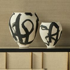 two black and white vases sitting on top of a shelf