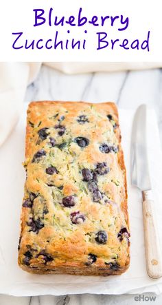 a loaf of blueberry bread sitting on top of a white napkin next to a knife and fork