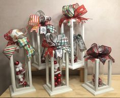 three white stands with red and green christmas decorations on them, one is holding ornaments in the shape of bells