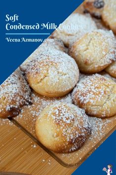 a wooden tray filled with powdered sugar covered muffins on top of a table