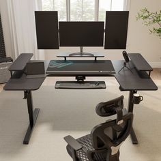 a computer desk with two monitors and a keyboard on it in front of a window