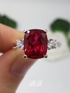 Made to order.  Please allow up to 3 weeks for the production of your selection. This listing is for a 925 non-plated sterling silver or non-plated gold three stone trellis ring with a high quality lab created ruby elongated cushion cut gemstone and high quality cubic zirconia diamond accent stones. Center Stone Gem Type: Lab Created Ruby Shape: Elongated Cushion Cut Size: 10x8mm Weight: 3.5 carats approximately Quality: AAA Hardness: 9 Mohs Accent Stones Gem Type: Lab Created Cubic Zirconia Diamonds Shape: Round Brilliant Size: (2) 3.5mm Color: White Quality: 6A Hardness: 8.5 Mohs Available in the following Metal Options (all metal are non-plated and solid) 925 Sterling Silver 10kt White Gold (non-rhodium plated) 10kt Yellow Gold 14kt White Gold (non-rhodium plated) 14kt Yellow Gold 14kt Trellis Ring, Emerald Ring Engagement Diamond, Elongated Cushion Cut, Elongated Cushion, Black Diamond Ring Engagement, Three Stone Ring, Golden Ring, Ruby Engagement Ring, Black Diamond Ring