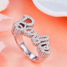 Elevate your style with our stunning 925 sterling silver Barbie ring. This exquisite piece features the word “Barbie” elegantly crafted in sparkling gemstones, creating a dazzling and glamorous accessory perfect for any fashion-forward individual. The ring’s intricate design and shimmering details make it a standout piece in any jewelry collection. Shipping:Takes 5-8 business days depending on stock, these beautiful rings are custom sized and made in small batches. If your size is in stock this item will ship immediately Product Details: Material: 925 Sterling Silver Gemstones: Clear Cubic Zirconia Design: Sparkling “Barbie” lettering Finish: Polished Size: Adjustable Occasion: Everyday wear, parties, and special occasions Why Choose This Ring? Elegance: The combination of sterling silver Silver Initial Ring With Diamond Accents For Wedding, Silver Wedding Initial Ring With Diamond Accents, Elegant Sparkling Cubic Zirconia Crystal Ring, Elegant Bling Crystal Ring For Party, Elegant Crystal Ring With Bling For Party, Dazzling Sterling Silver Jewelry For Promise, Dazzling Sterling Silver Promise Jewelry, Elegant Party Crystal Ring With Bling, Elegant Sparkling Crystal Promise Ring