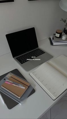 an open laptop computer sitting on top of a desk next to a notebook and pen