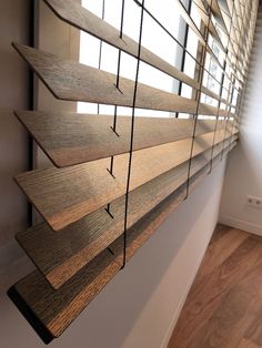 wooden blinds are hanging on the side of a wall in a room with wood flooring