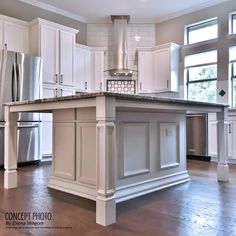 a large kitchen with white cabinets and stainless steel refrigerators in it's center island