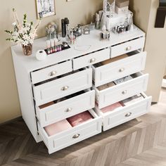 a white dresser with drawers and pictures on the wall