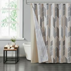 a bath room with a shower curtain and a table in front of a window that has candles on it