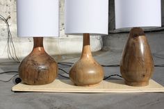 three wooden lamps sitting on top of a table next to a white lamp shade holder