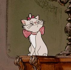 a cartoon cat with a pink bow sitting on top of a table