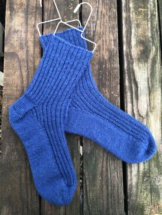 a pair of blue socks sitting on top of a wooden floor next to a hanger