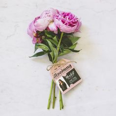 a bouquet of pink flowers sitting on top of a white table next to a book