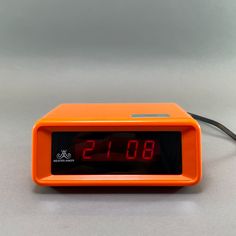 an orange alarm clock sitting on top of a table