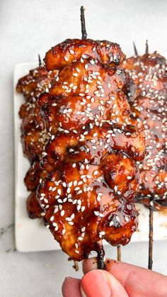 someone is holding some kind of meat on a stick with sesame seeds and sesame seeds sprinkled all over it