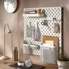 a desk with a clock and various office supplies on the pegboard next to it