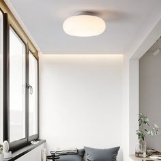 a living room with white walls and flooring next to a window filled with plants