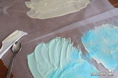 some blue and white frosting on top of paper with a spoon next to it