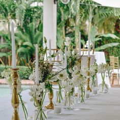 white flowers and candles are lined up on a table in front of an outdoor pool