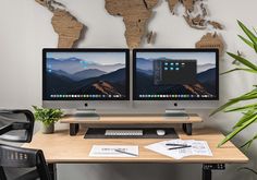 two computer monitors sitting on top of a wooden desk