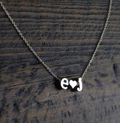 a necklace with the word love written on it and a heart in the middle, sitting on a wooden surface