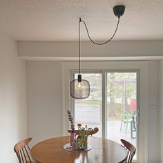 a dining room table with four chairs and a light fixture hanging from it's ceiling