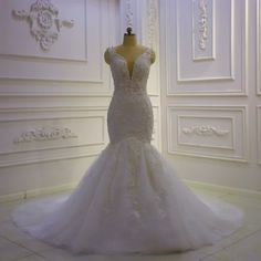 a wedding dress is displayed on a mannequin in front of a white wall