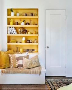 a living room with white walls and yellow bookshelves on the wall next to a bed