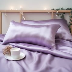 a cup of coffee sits on the edge of a bed with purple sheets and pillows