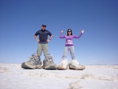 two people standing in the snow with their hands up and one person sitting on top of them