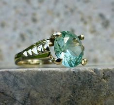 This beautiful and elegant sea foam green spinel ring holds true to the timeless designs of the late 1960's Mid-century period. The lines are strong and romantic, with just the right curves and flash to catch your eye. A 10 karat gold setting accentuates a large, light green synthetic spinel solitaire. Shifts and changes to the light and color give this ring a rich organic feel with layers of brightness and sparkle. Such an outstanding piece for any green stone lover! The stone measures 9mm and has great flashes of teal, mint and aqua. The rise off the finger measures 6.6mm. This beautiful piece has been well cared for and shows no large chips to the center stone. The inside of the band is no longer stamped but tests as 10 karat gold. The band has a nice thickness and the stone is secure i Green Topaz Ring For Formal Occasions, Formal Green Topaz Ring, Unique Green Emerald Ring For Formal Occasions, Green Topaz Ring With Center Stone, Green Topaz Ring With Prong Setting For Anniversary, Heirloom Green Sapphire Ring, Classic Green Topaz Ring Gift, Classic Green Topaz Ring For Gift, Vintage Emerald Ring For Promise