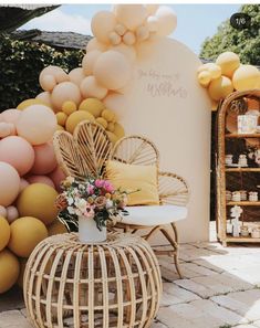 a wicker chair and table with balloons on the wall in front of an outdoor venue