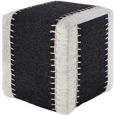 a black and white square ottoman sitting on top of a wooden floor next to a wall