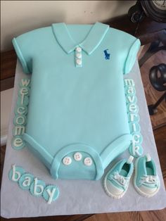 a cake that is shaped like a baby's bodysuit and shoes on top of it