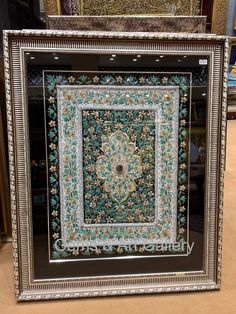 an ornate frame with blue and green flowers on it in front of other framed pictures